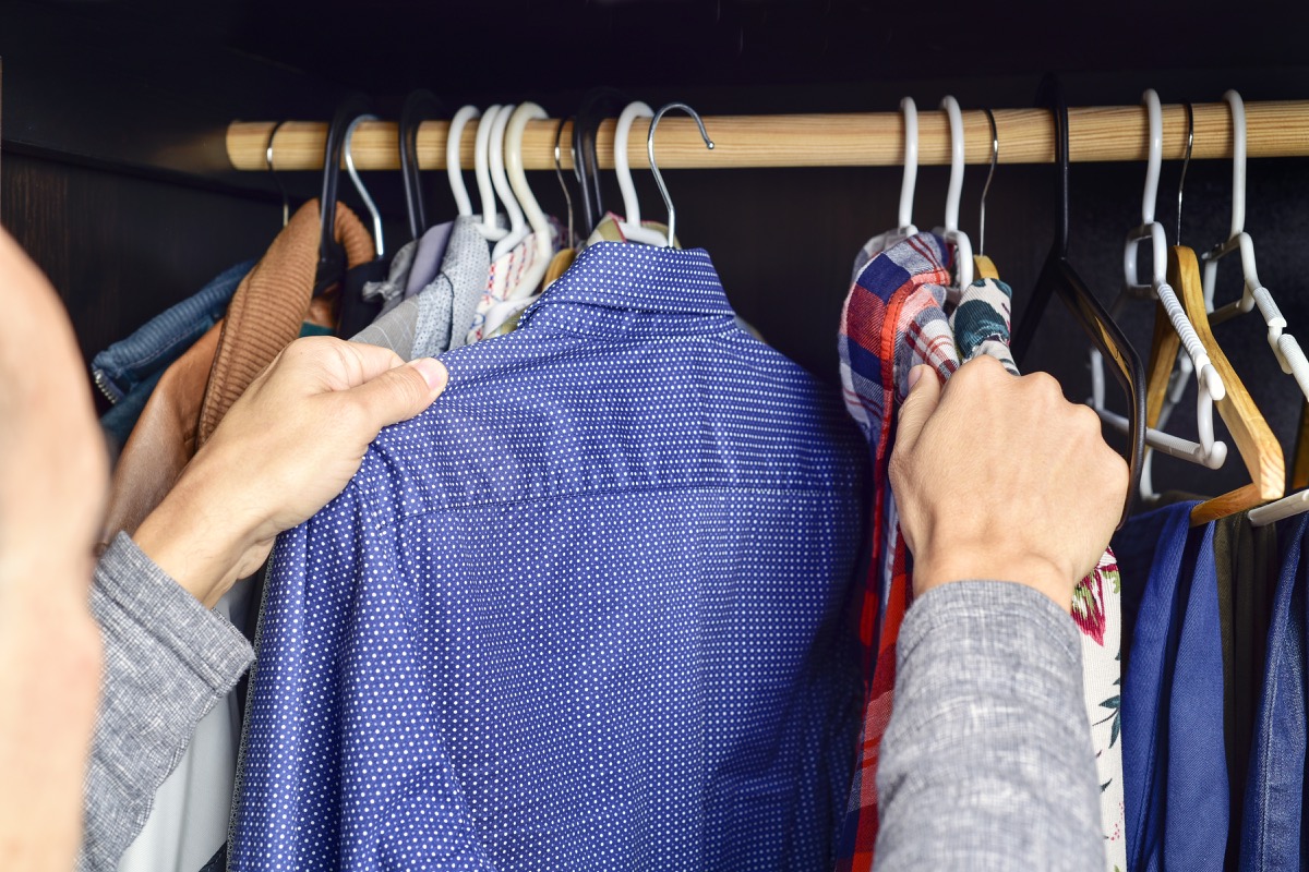 Man looking through his shirts in his closet
