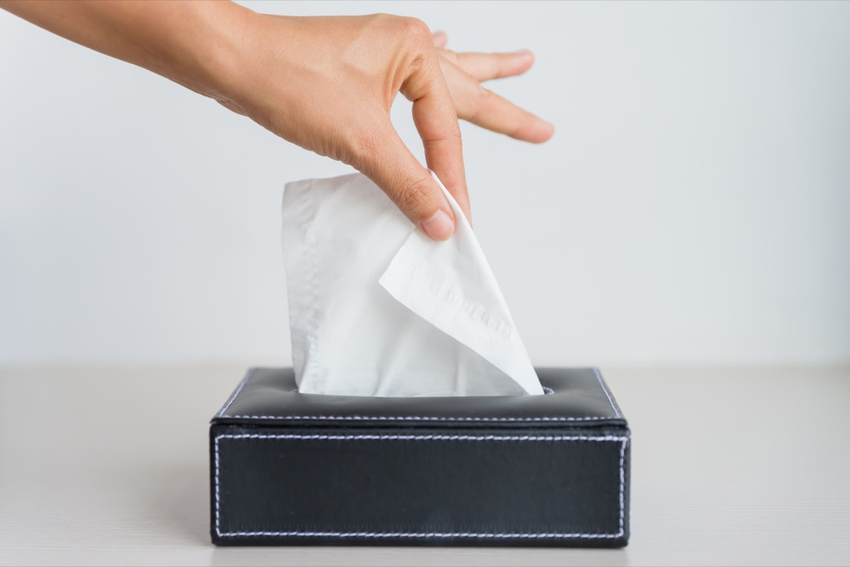 Man pulling a single tissue from black tissue box