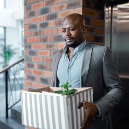 man leaving work with box after quitting job