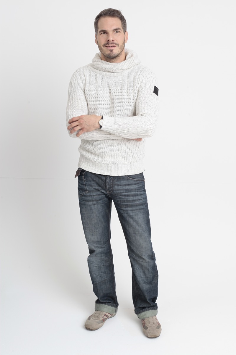 Man in his 40s wearing cuffed folded jeans and a white sweater