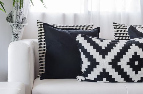 Multiple different black and white patterned pillows resting on a white couch