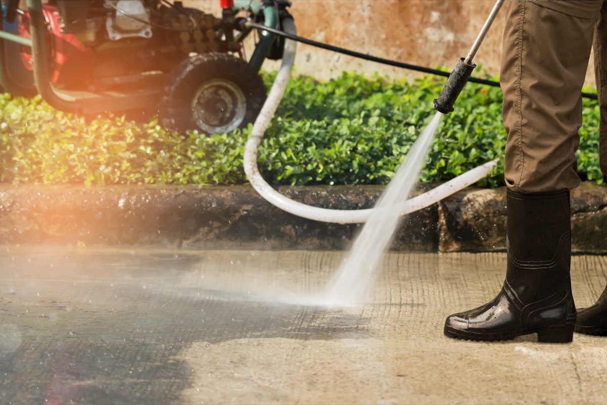 Worker cleaning driveway with gasoline high pressure washer splashing the dirt,professional cleaning services.High pressure cleaning, lower body. 