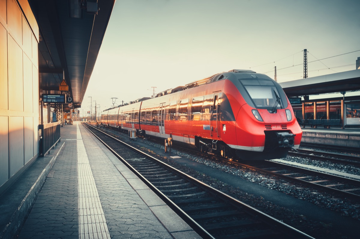 Beautiful railway station with modern red commuter train at colorful sunset in Nuremberg , Germany. Railroad with vintage toning