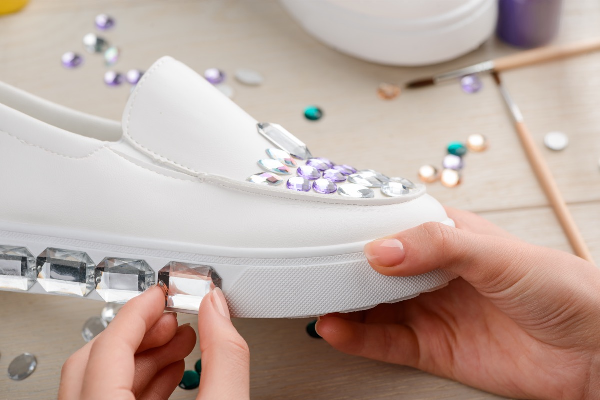 a teenage girl bedazzling a white pair of slip on shoes