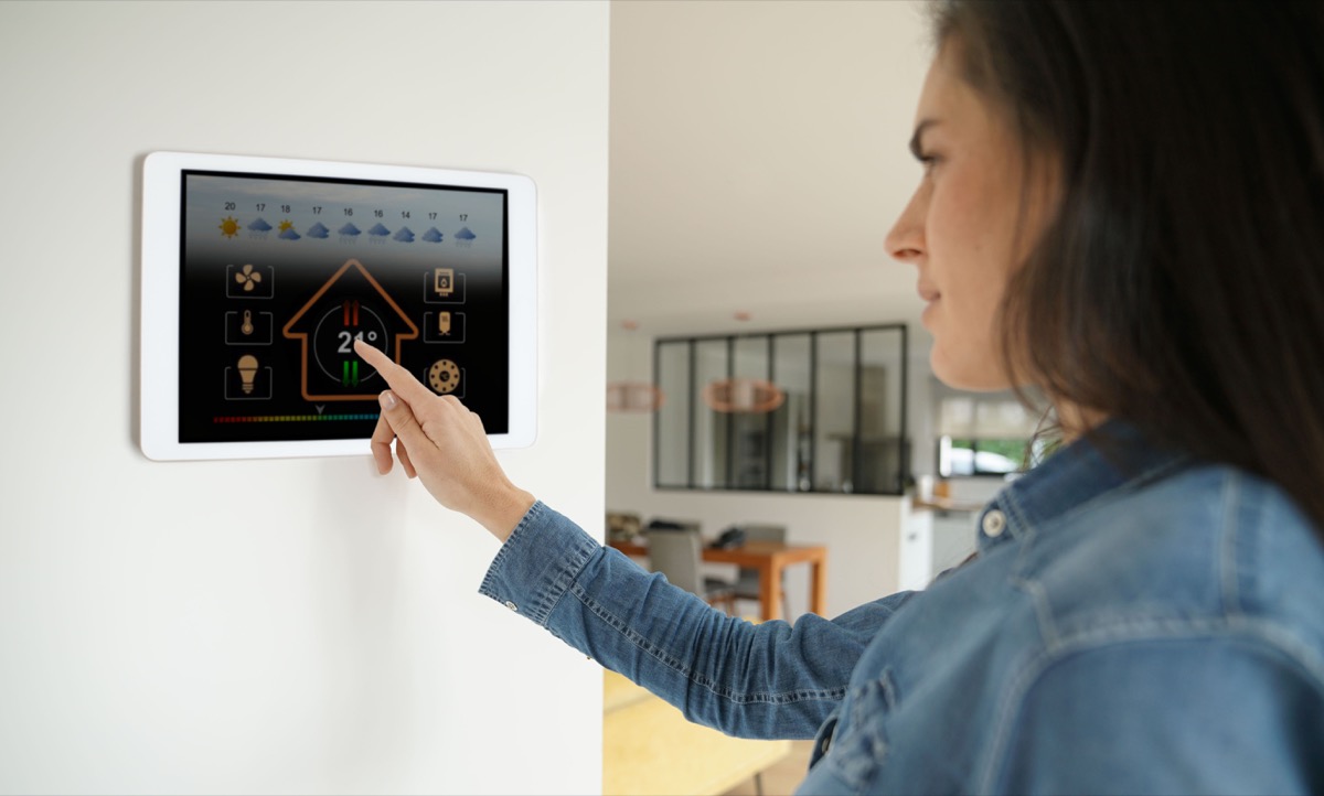 Woman using smart technology thermostat in her home