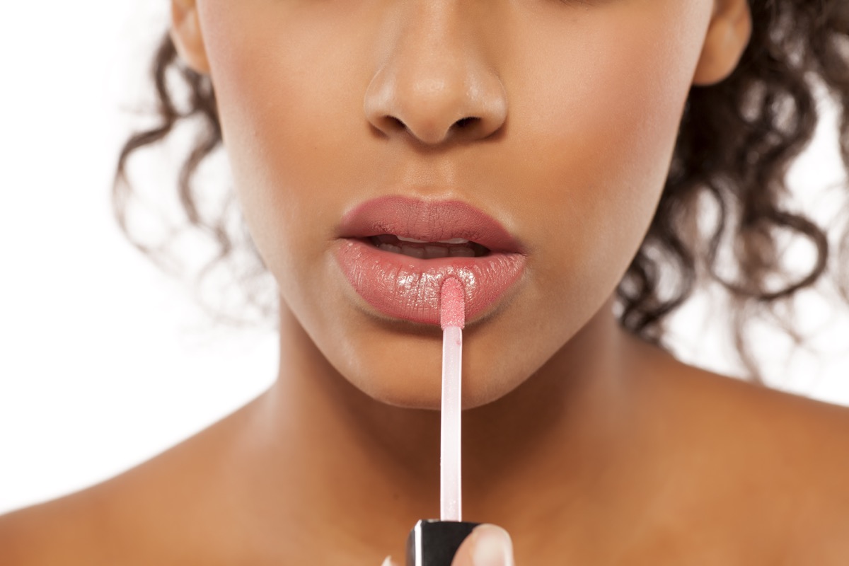 Woman applying nude shimmery lip gloss