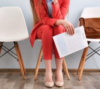 woman wearing a red suit waiting for an interview, holding her resume