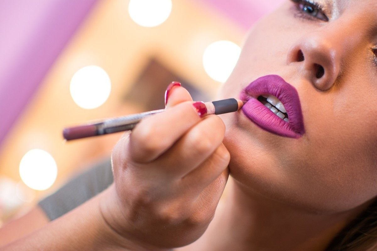 Beautiful woman applying lip liner to lips. Close up