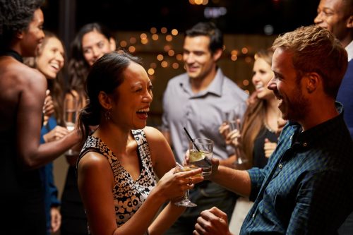 woman and man laughing in conversation at a cocktail party, bad jokes