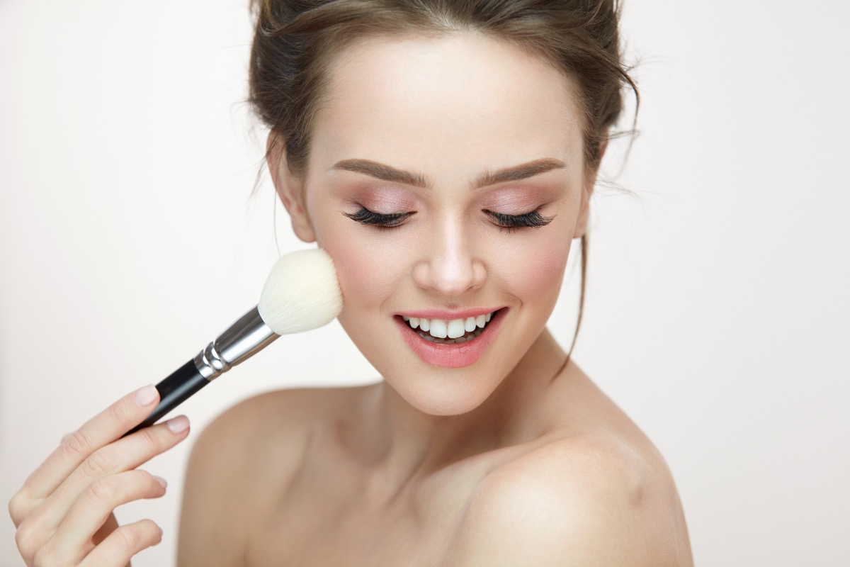 Facial Makeup. Closeup Of Beautiful Young Female Model Putting Blush With Cosmetic Brush. Portrait Of Attractive Healthy Girl With Pure Clean Skin And Natural Make-Up. Beauty Concept