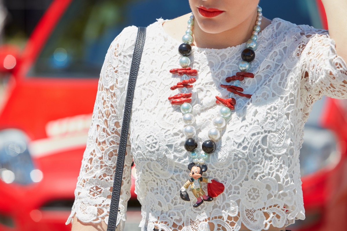 woman wearing a necklace with a mickey mouse charm and white top