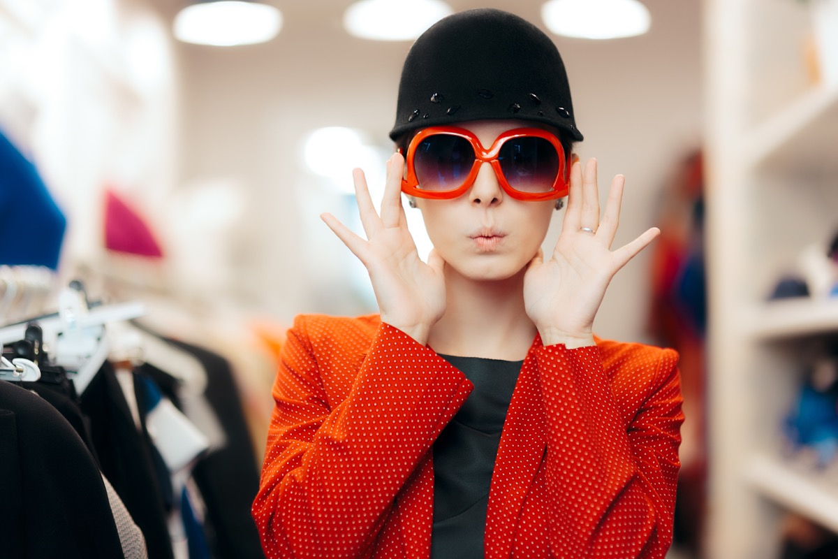 a woman trying on oversized red sunglasses in a store health tweaks over 40