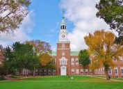 Looking down the Dartmouth Green with trees beginning to show fall colors and a blue sky with puffy white clouds on a nice autumn day the Baker Library and its bell tower is in the background. - Image