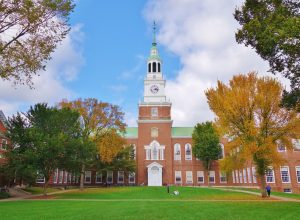 Looking down the Dartmouth Green with trees beginning to show fall colors and a blue sky with puffy white clouds on a nice autumn day the Baker Library and its bell tower is in the background. - Image