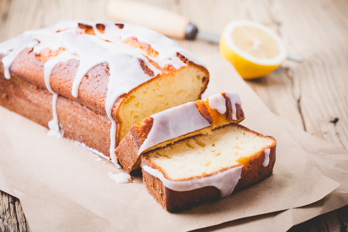 Homemade glazed lemon pound cake on rustic wooden table, sliced and ready to eat - Image