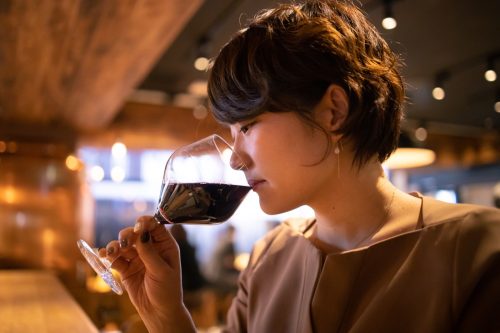 Junge Frau trinkt Rotwein im Pub