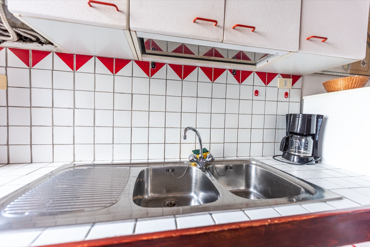 outdated kitchen with old red and white tile counter
