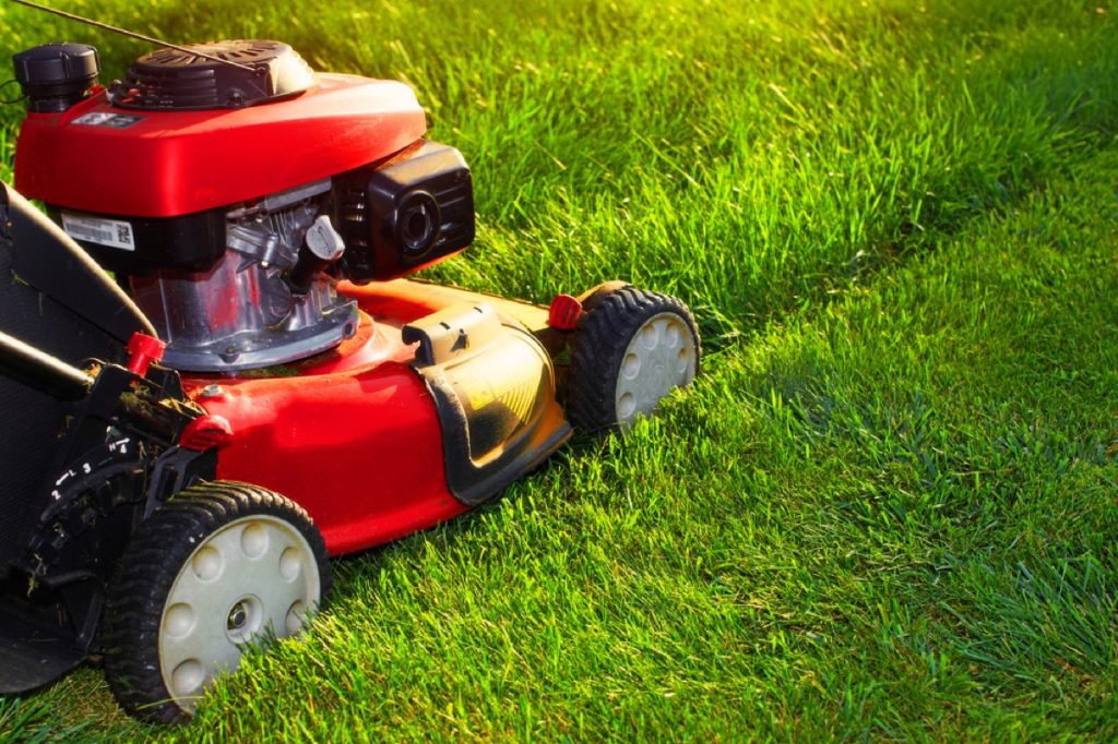 person mowing lawn with electric lawnmower, fire prevention tips