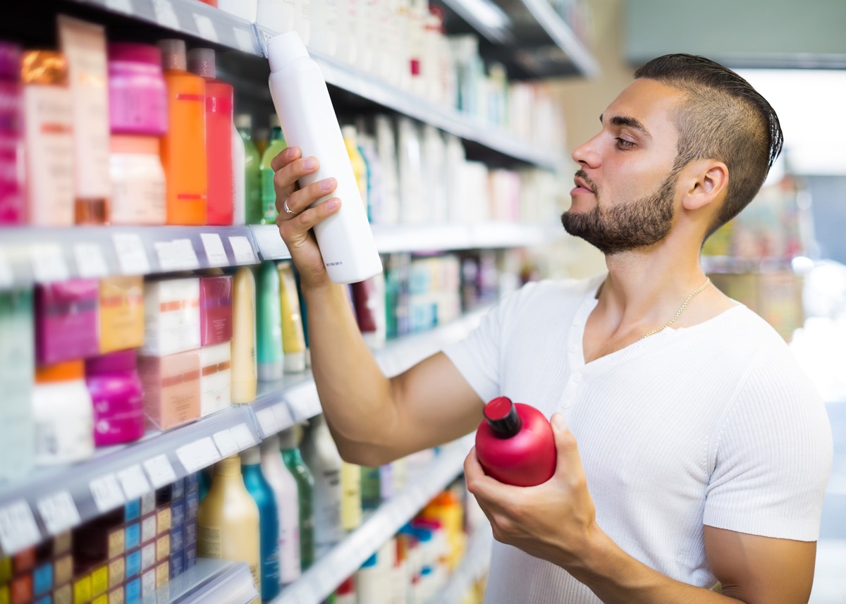 Attractive man buying shampoo in shopping mall - Image