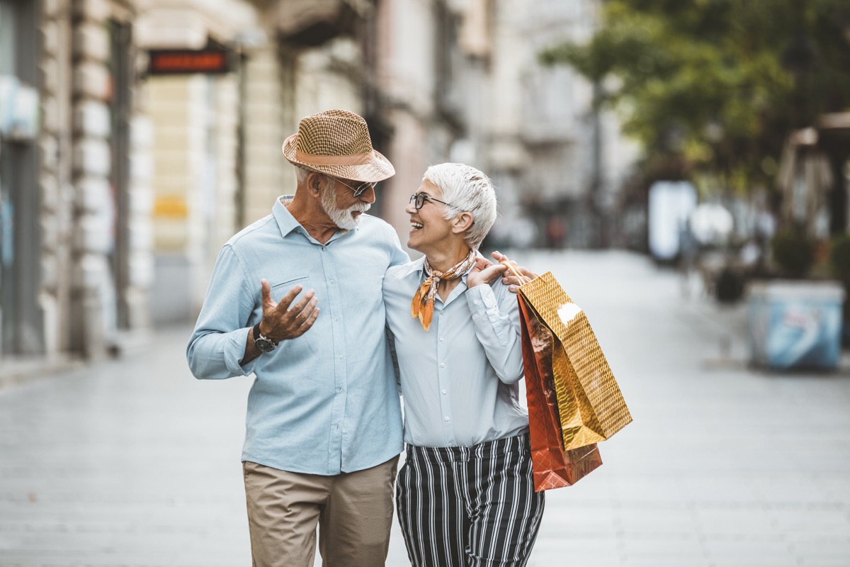 older couple walking together with shopping bags after going shopping