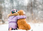 little girl hugging dog in winter, skills parents should teach kids