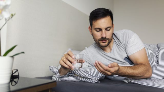 Man taking pills in bed