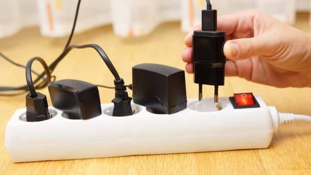 white hand unplugging charger from power strip