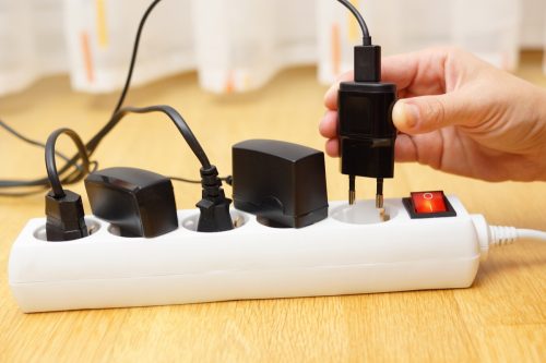 white hand unplugging charger from power strip