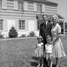 1960s suburban family in black and white photo standing in front of huge suburban home