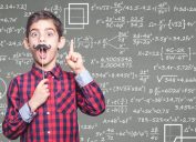 Little boy with fake mustache standing in front of chalkboard with math equations