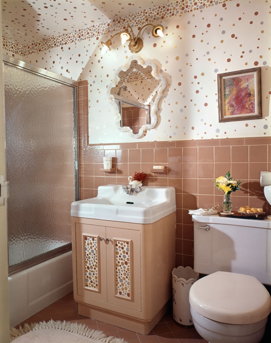 1960s huge bathroom with shower and tub combo, single sink, and toilet, adorned with pink tiles