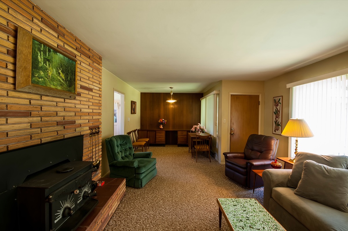 1960s huge suburban home's living room with fireplace, couch, arm chair, and coffee table