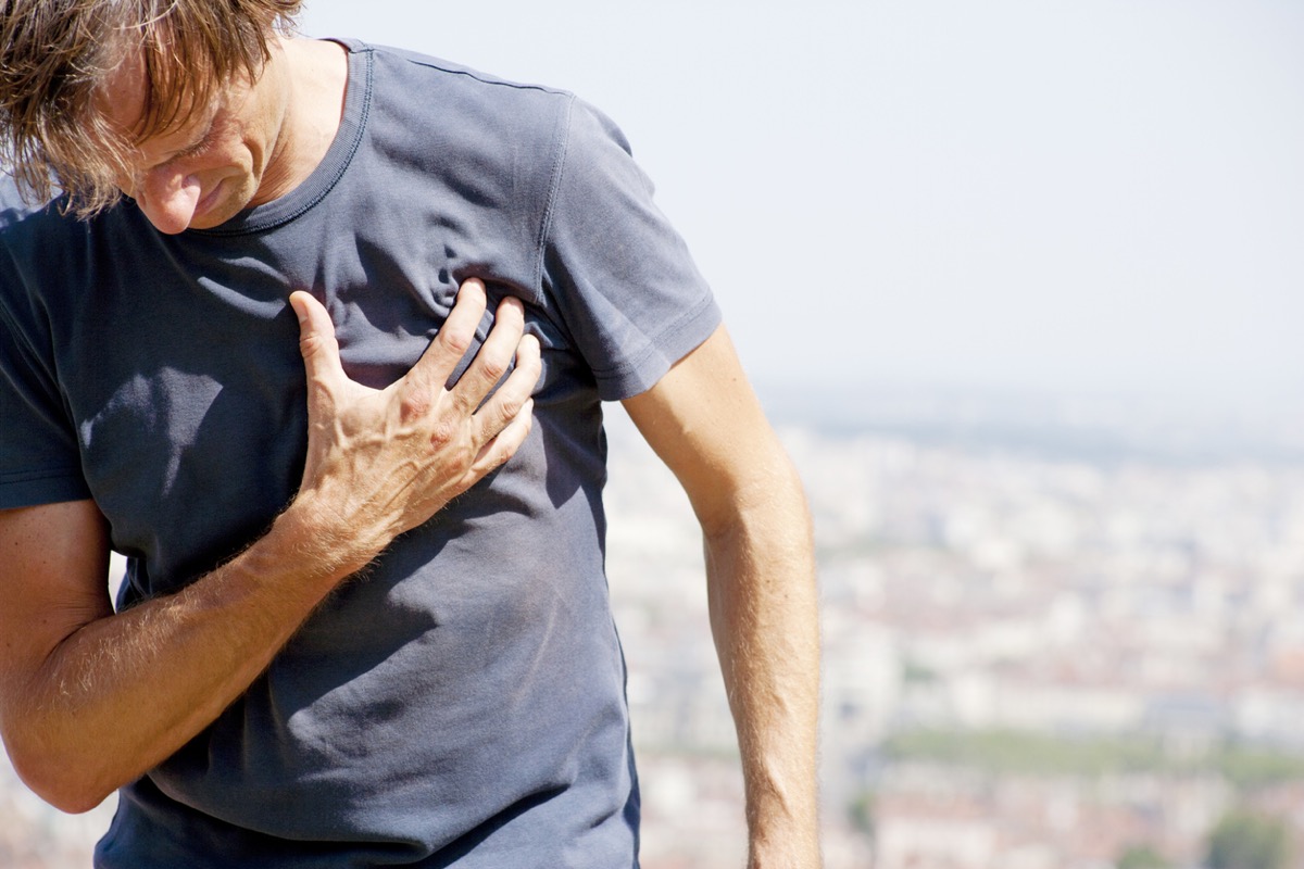 middle aged man holds heart while outside