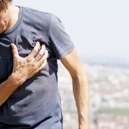 middle aged man holds heart while outside