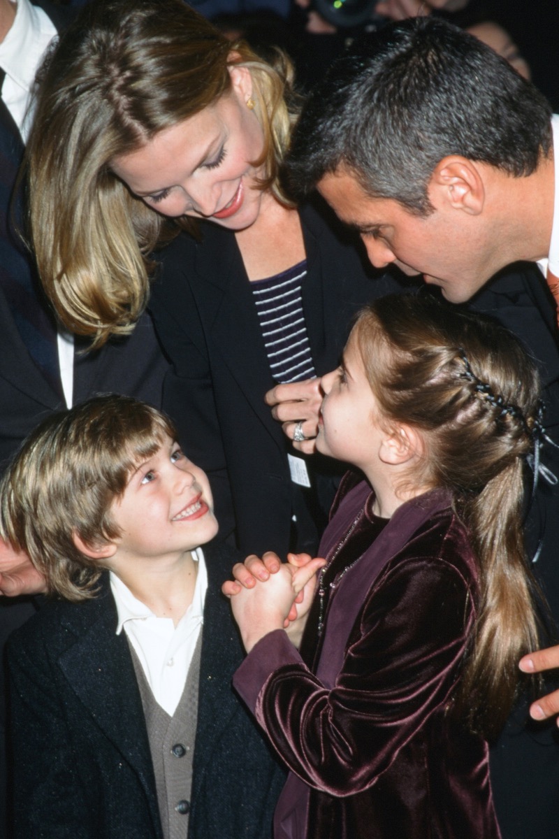 Celebrities Michelle Pfeiffer and George Clooney lean over their One Fine Day Costars Alex D Linz and Mae Whitman at 1996 premiere