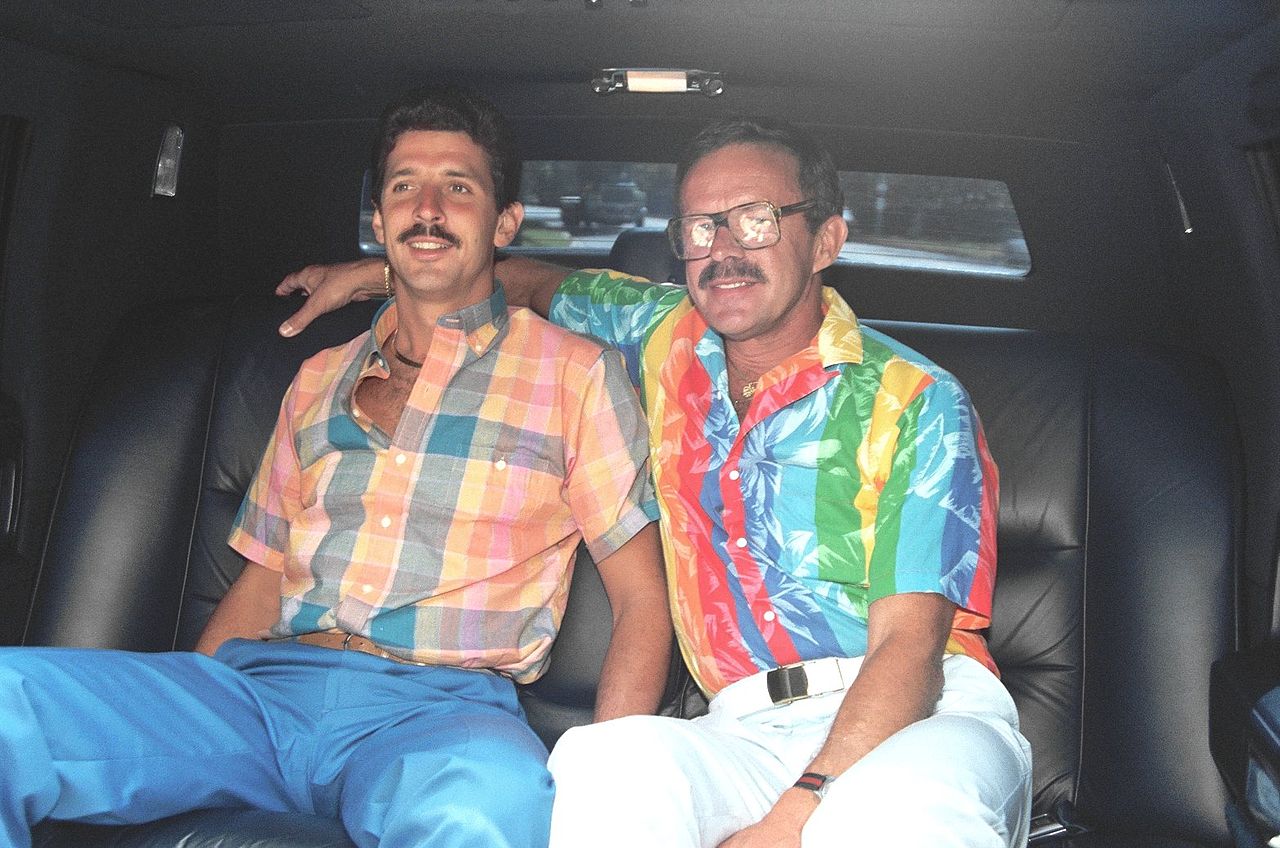 two men in the back of the car, one wearing cazal glasses, 1980s fashion