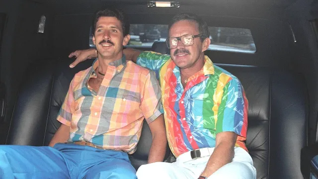 two men in the back of the car, one wearing cazal glasses, 1980s fashion