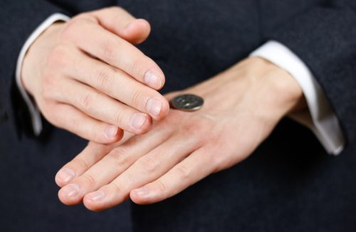 man uncovering a coin toss on his hands, terrible decisions