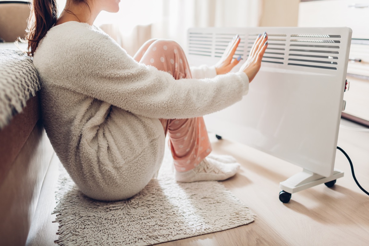 Woman warming her hands with a heater