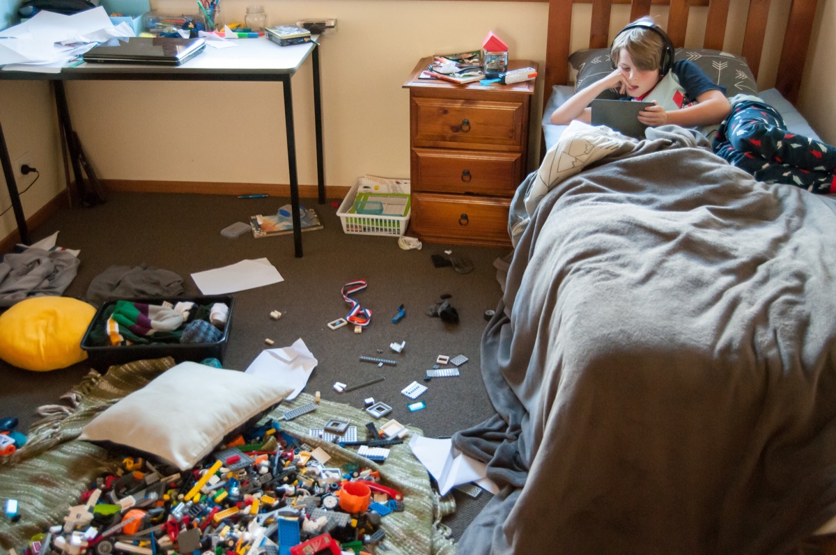 kid laying on his bed in a messy room