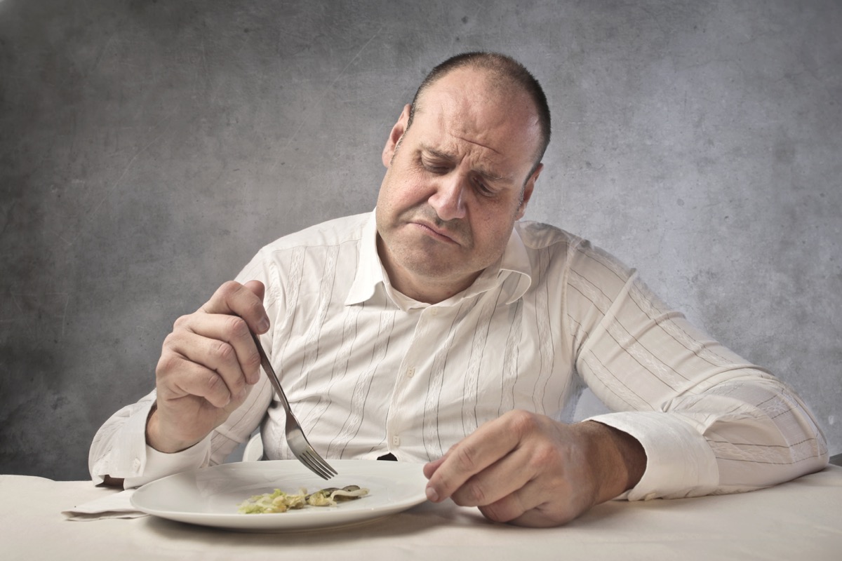 Man looking upset because he has to eat vegetables on a diet