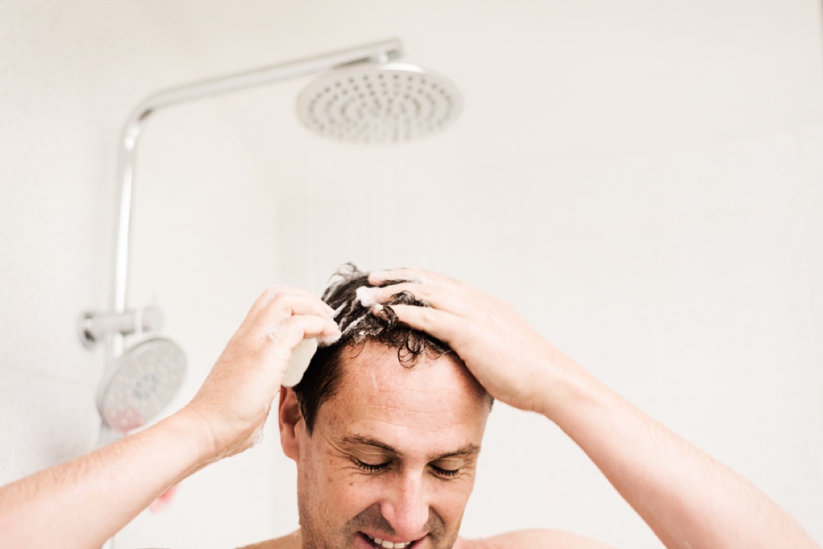 middle aged man soaps up hair in shower