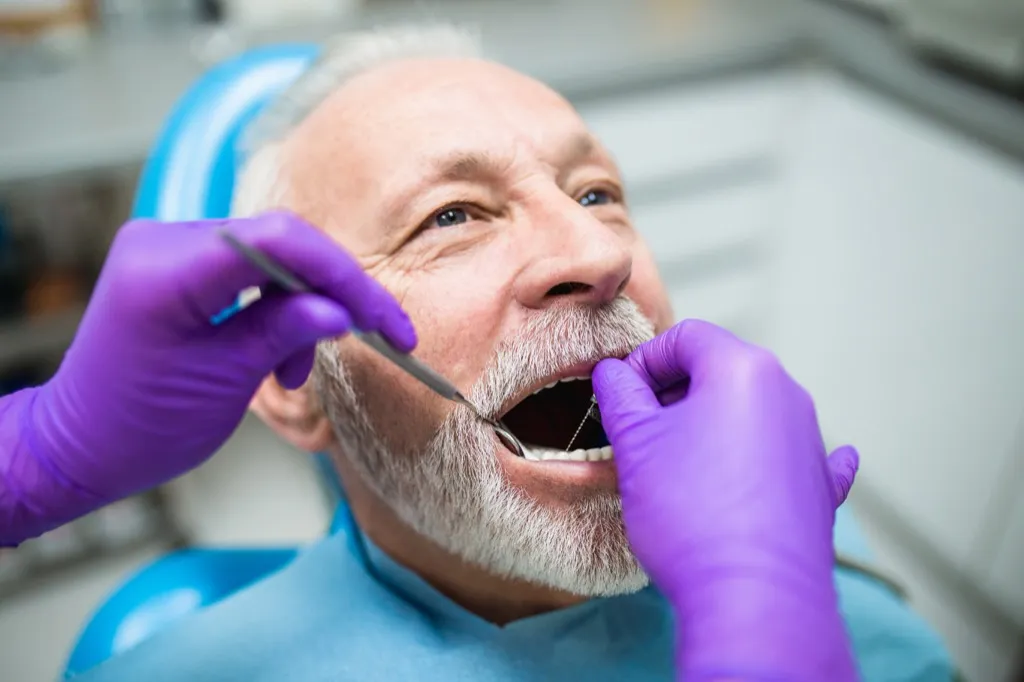 Възрастен мъж при зъболекар, проверяващ венците си, здравни въпроси след 40