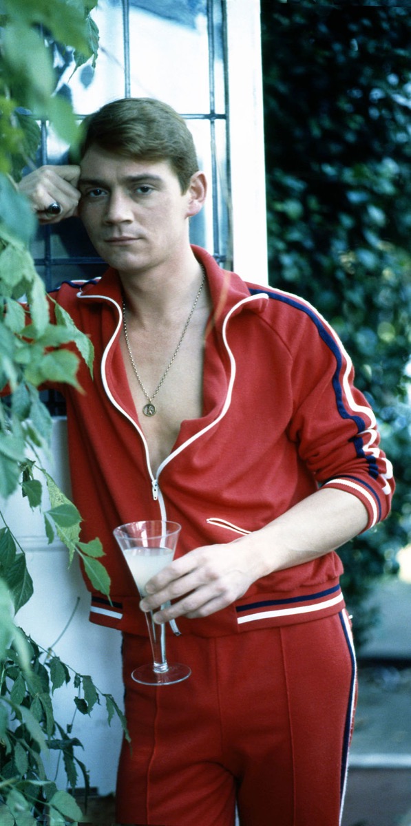 anthony andrews in his garden in wimbledon england wearing a red tracksuit, 1980s fashion