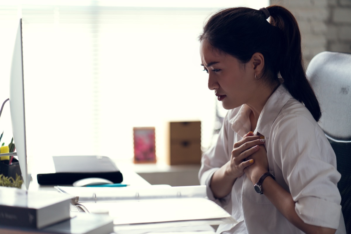 a woman clutching her chest in an office