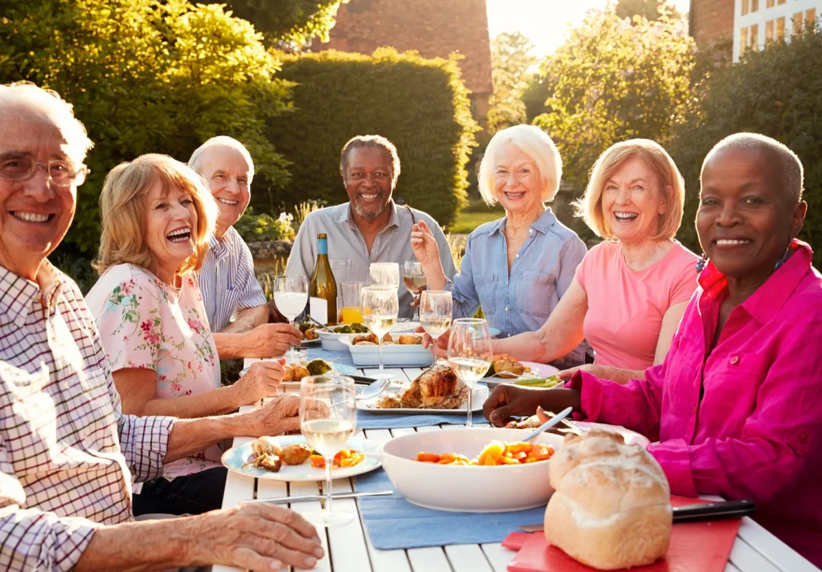 seniors of white and black races share outdoor dinner party