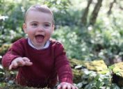 Prince Louis in maroon sweater sits in wooded area, official photo by Kate Middleton