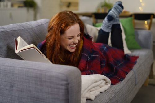 Woman laughing as she reads a book