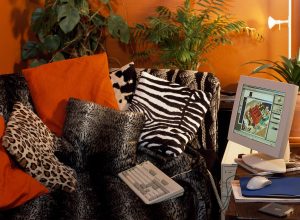 Animal print cushions on sofa in a nineties bed-sitting room with a computer on a low table