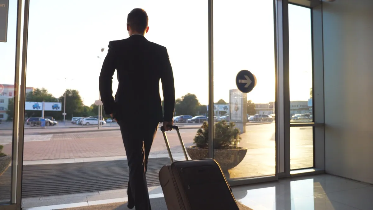 man walking through automatic door with suitcase, old inventions